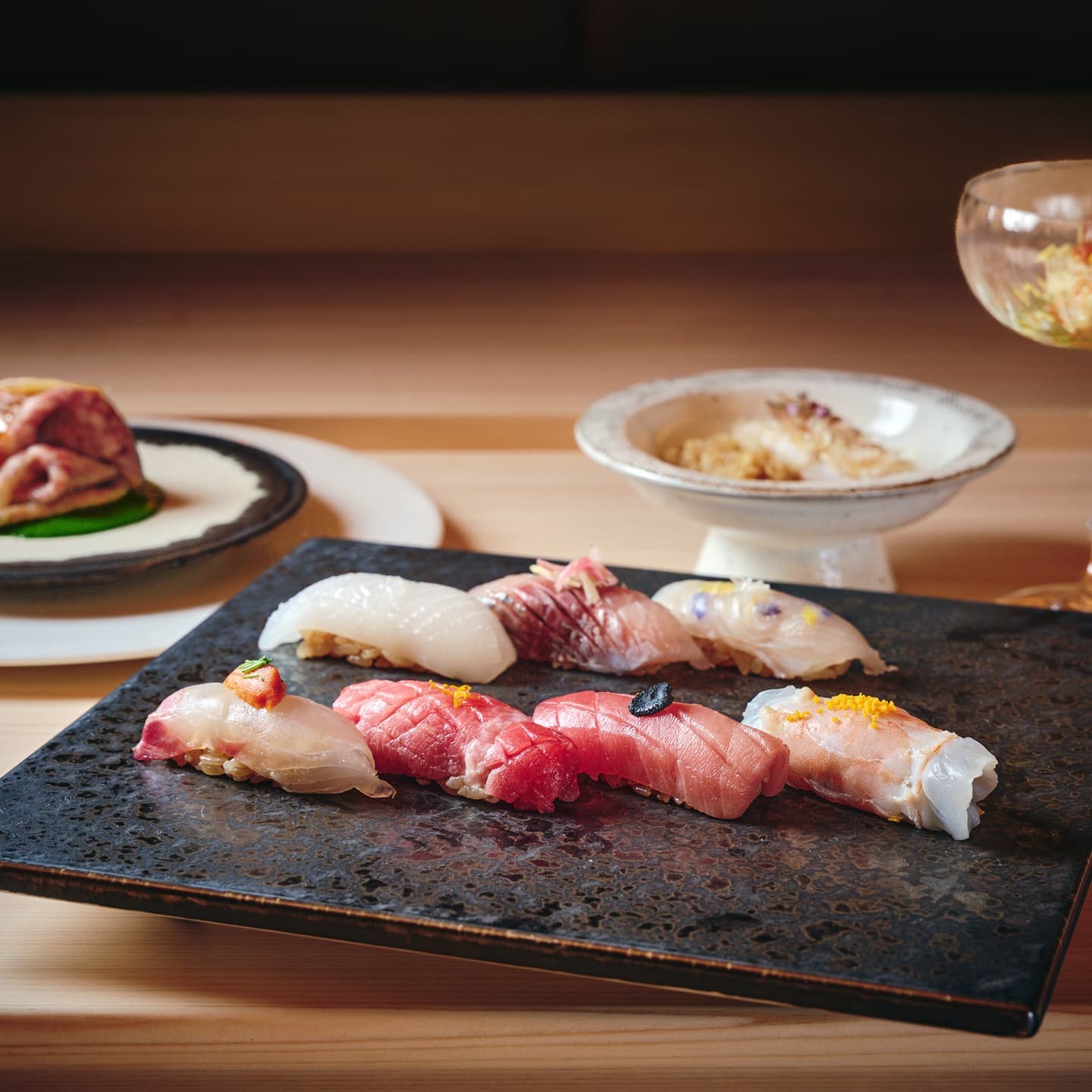黒い石皿に美しく並べられた江戸前寿司の盛り合わせ、ネタの鮮度と繊細な飾り切りを強調した高級感のある料理撮影