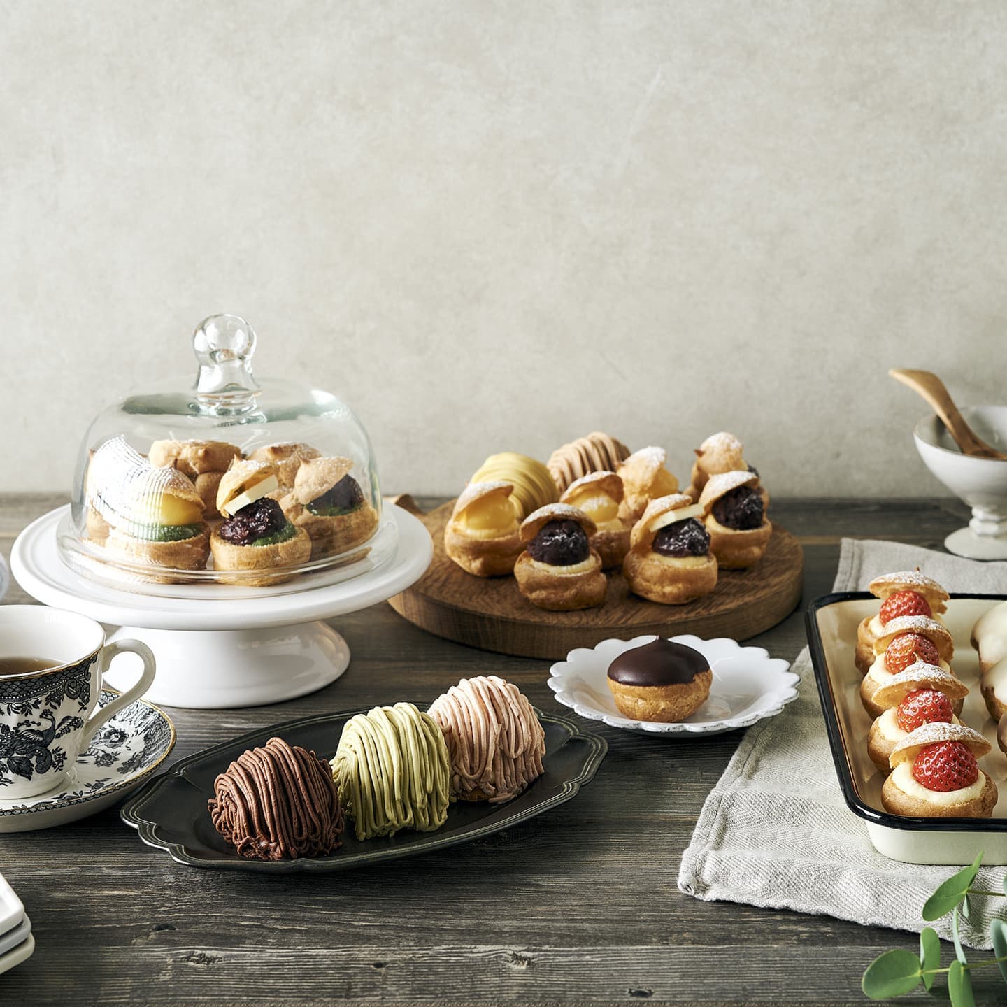 木目調のテーブルに、アンティークな器やコーヒーを配したシュー菓子の俯瞰撮影。素材ごとに異なるプロップスを厳選し、午後のティータイムを上質な物語として構成したライフスタイルビジュアル