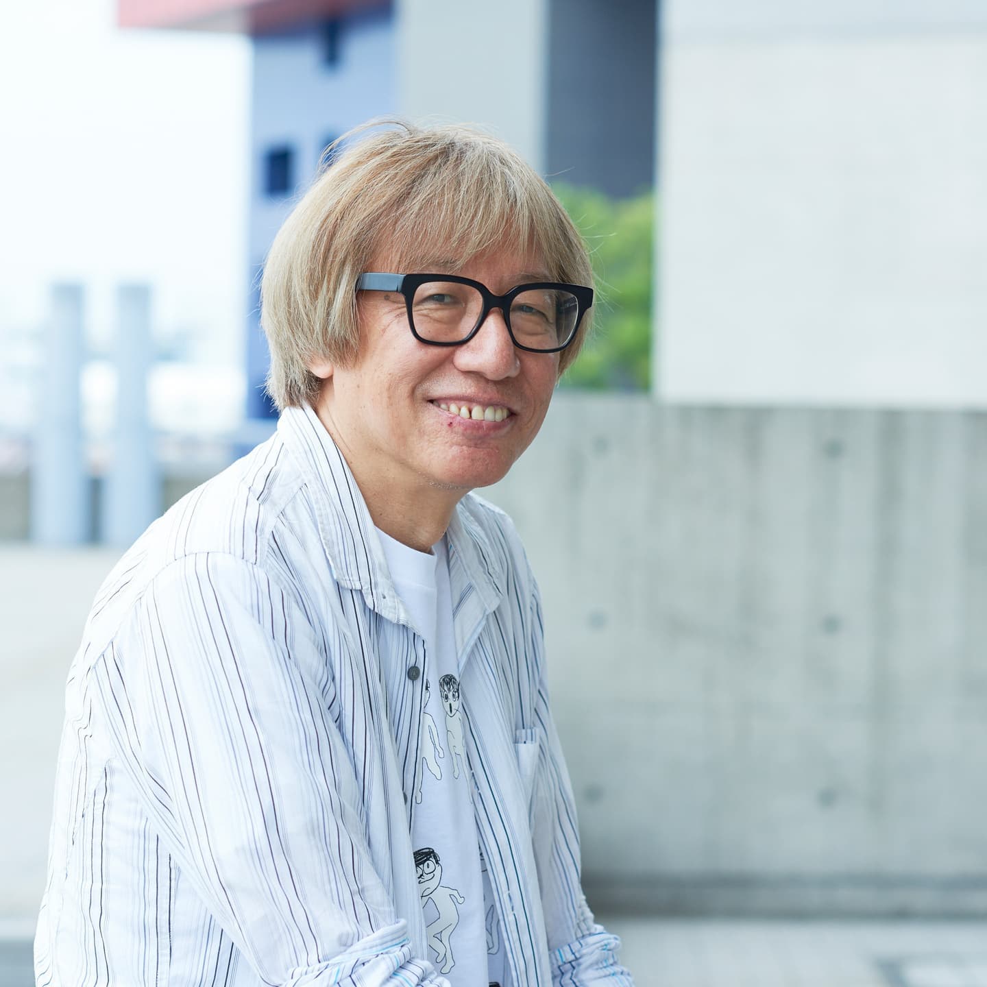 柔らかな屋外の光で撮影した、親しみやすさを感じさせるクリエイターのポートレート。日常の延長線上にある自然な表情を捉えたビジュアル制作。