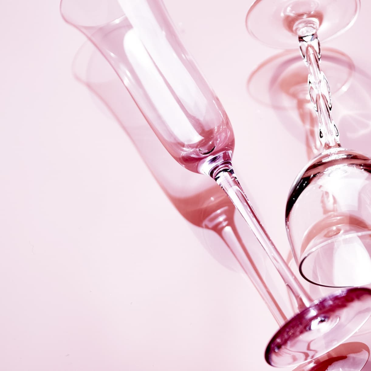 大阪の撮影スタジオによる商品撮影。ピンクの背景に映えるグラスの透過光と影を活かした、質感重視のスティルライフ・フォト。