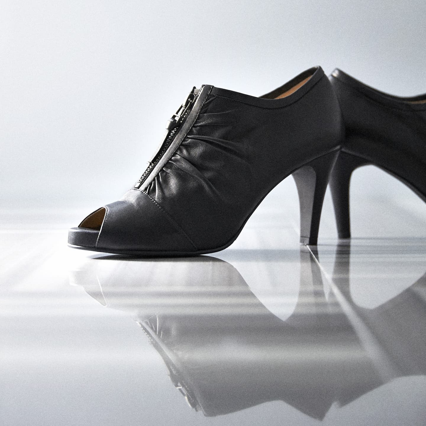 大阪のスタジオで撮影された、クリアなアクリル上に整然と並ぶ多色展開のサンダル。ノイズを排したライティングにより、エナメルの光沢とフォルムの美しさを正確に描き出した、D2Cブランド向けのカタログビジュアル。