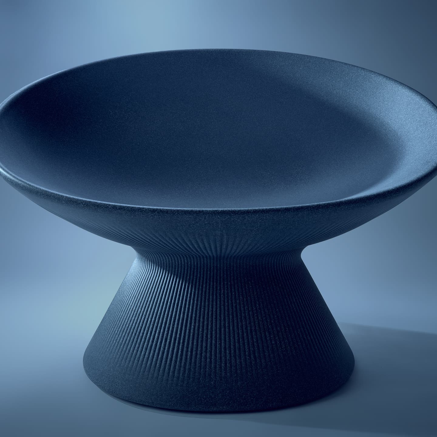 大阪のスタジオで撮影された、彫刻的なフォルムを持つネイビーのスツールのスティルライフ。マットな質感と繊細な縦ラインのディテールを、静謐なライティングで浮き彫りにしたプロダクト写真。