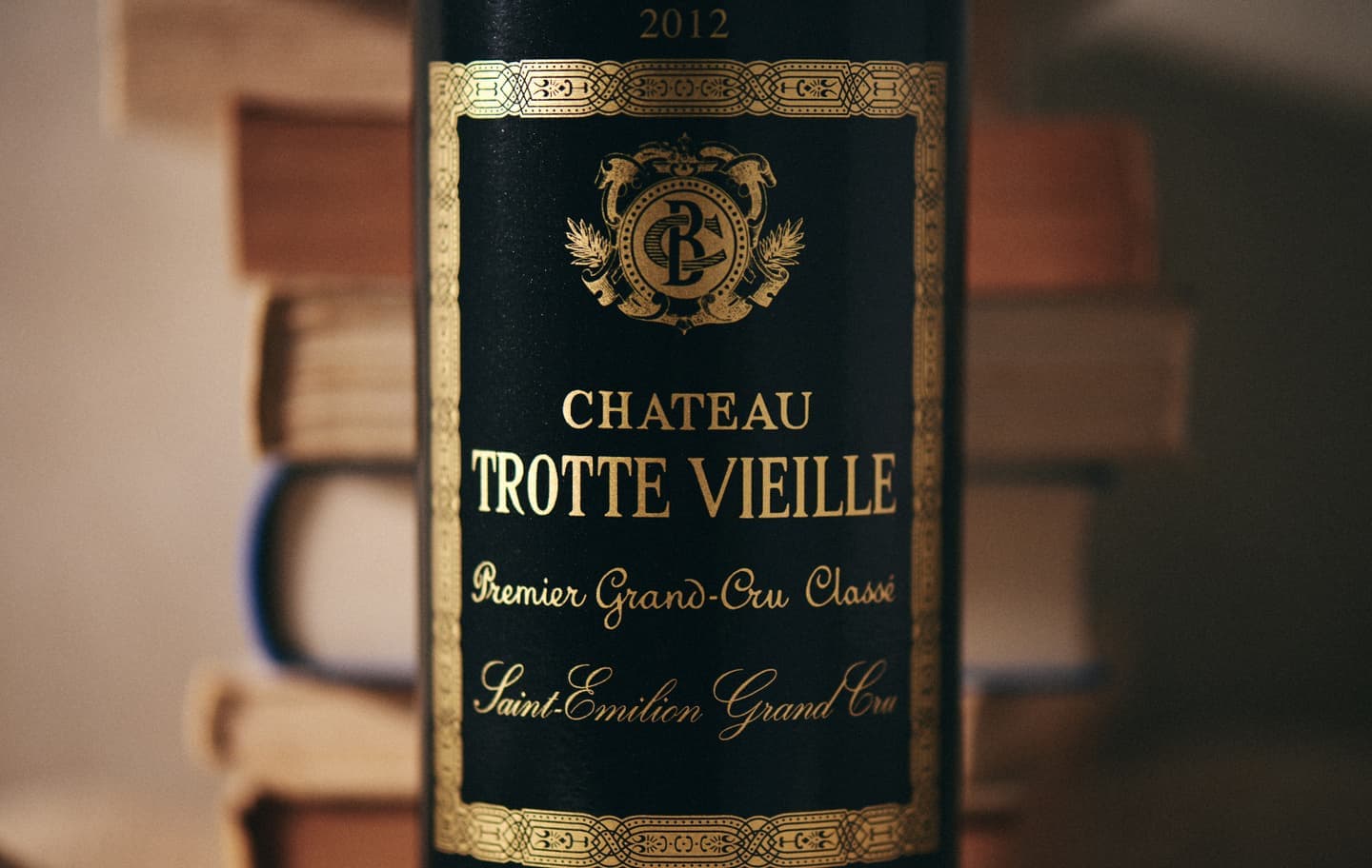 シャトー・トロット・ヴィエイユのワインラベルのアップと背後に積み重なる古書の質感